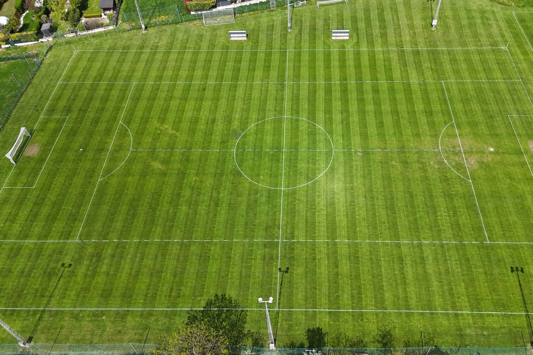 Luftaufnahme eines leeren, gut gepflegten Fußballplatzes mit klaren weißen Linien und üppigem Gras, nur wenige Schritte vom stilvollen Hotel Galántha und den eleganten Zimmern in der Nähe von Schloss Esterházy entfernt.