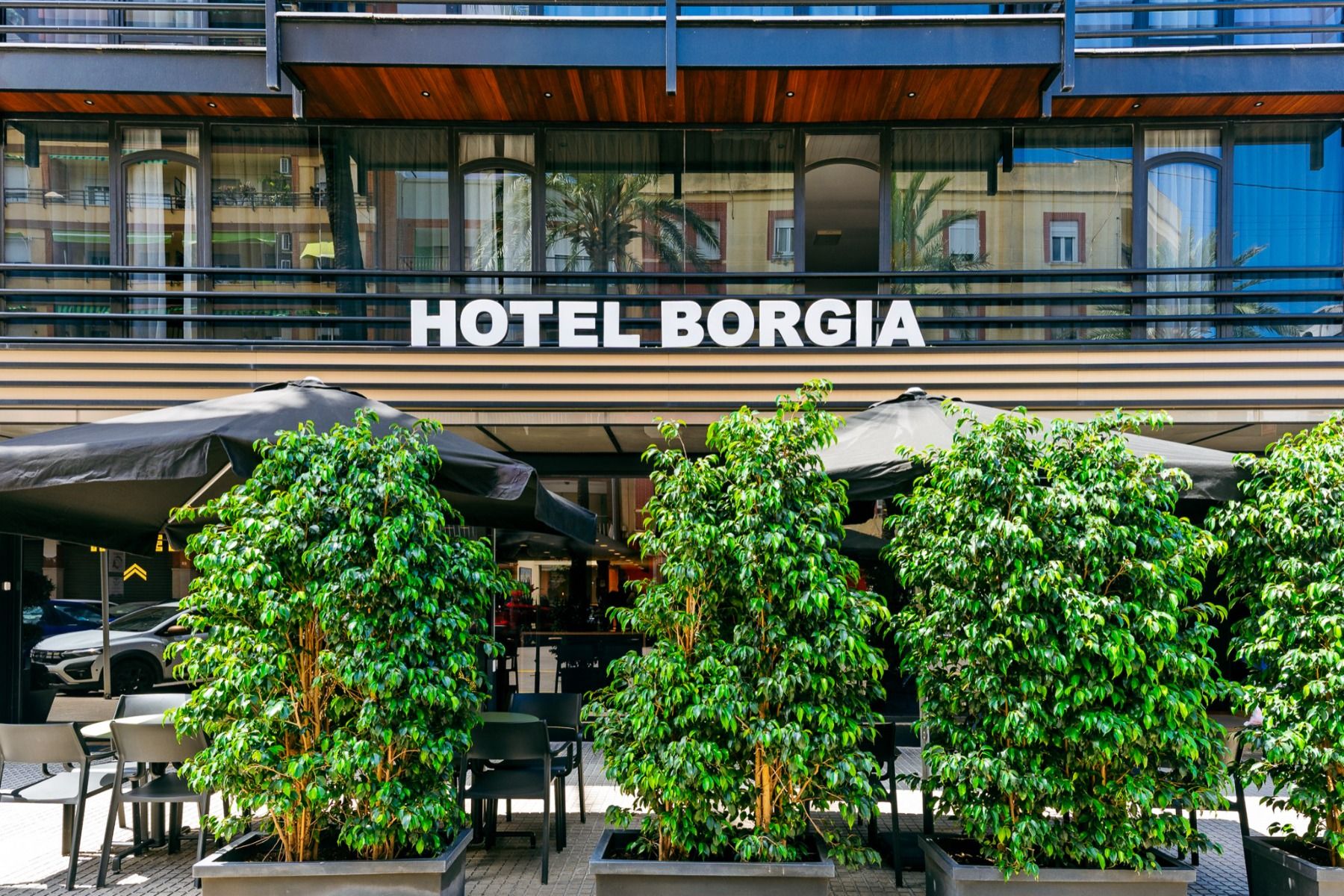 Die Fassade des Hotels Borgia ***, das bei Fußballmannschaften wegen seiner einladenden Atmosphäre während Trainingslagern sehr beliebt ist, besticht durch große Grünpflanzen am Eingang, von schwarzen Sonnenschirmen beschattete Sitzbereiche im Freien und 