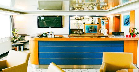 Das Hotel Marttel*** ist ein modernes wei&szlig;es Geb&auml;ude mit vielen Fenstern in der N&auml;he des gr&uuml;nen Kunstrasen-Fu&szlig;ballplatzes, umgeben von B&auml;umen und H&uuml;geln, mit Wohnh&auml;usern im Hintergrund unter einem teilweise bew&ouml;lkten Himmel, nahe der deutschen Grenze.