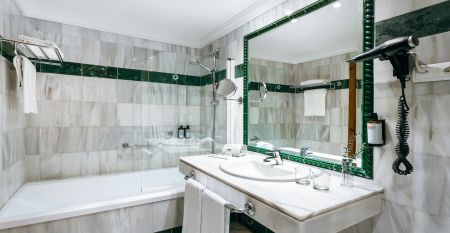 Ein hohes, gelbes Hotel Sol Guadalmar mit Balkonen blickt auf einen klaren, blauen Au&szlig;enpool, umgeben von Palmen und gr&uuml;nen Rasenfl&auml;chen unter einem sonnigen Himmel - perfekt f&uuml;r Ihren Aufenthalt in diesem zentrumsnahen 4 Sterne Hotel Malaga.