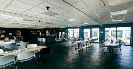 Luftaufnahme des Watersley Sports & Talentpark, eines weitläufigen historischen Komplexes mit grauem Dach, eingebettet in eine grüne Landschaft. Der Campus umfasst ein kapellenartiges Gebäude, erstklassige Trainingseinrichtungen und bietet einen Blick auf