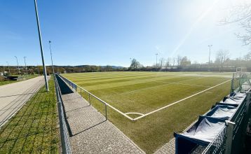 Hotel Empfinger Hof, med rødt tegltak og kvistevinduer, ønsker gjester velkommen til Fußballtrainingslager. Et "Hotel Restaurant"-skilt kroner bygningen, med trær og en asfaltert inngang som tilbyr gute Verpflegung og solrik varme.