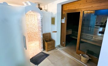 Ein leuchtend gelbes Gebäude in Neuhofen an der Ybbs mit Steg, Leiter und schwarzem Schlauchboot liegt an einem ruhigen Teich im Grünen - im familiengeführten Hotel Perbersdorfer Heuriger genießen die Menschen diese Szene.