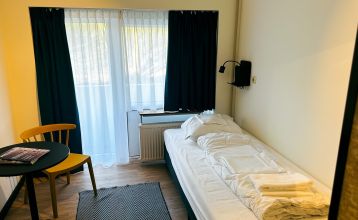 Luftaufnahme des Watersley Sports & Talentpark, eines weitläufigen historischen Komplexes mit grauem Dach, eingebettet in eine grüne Landschaft. Der Campus umfasst ein kapellenartiges Gebäude, erstklassige Trainingseinrichtungen und bietet einen Blick auf