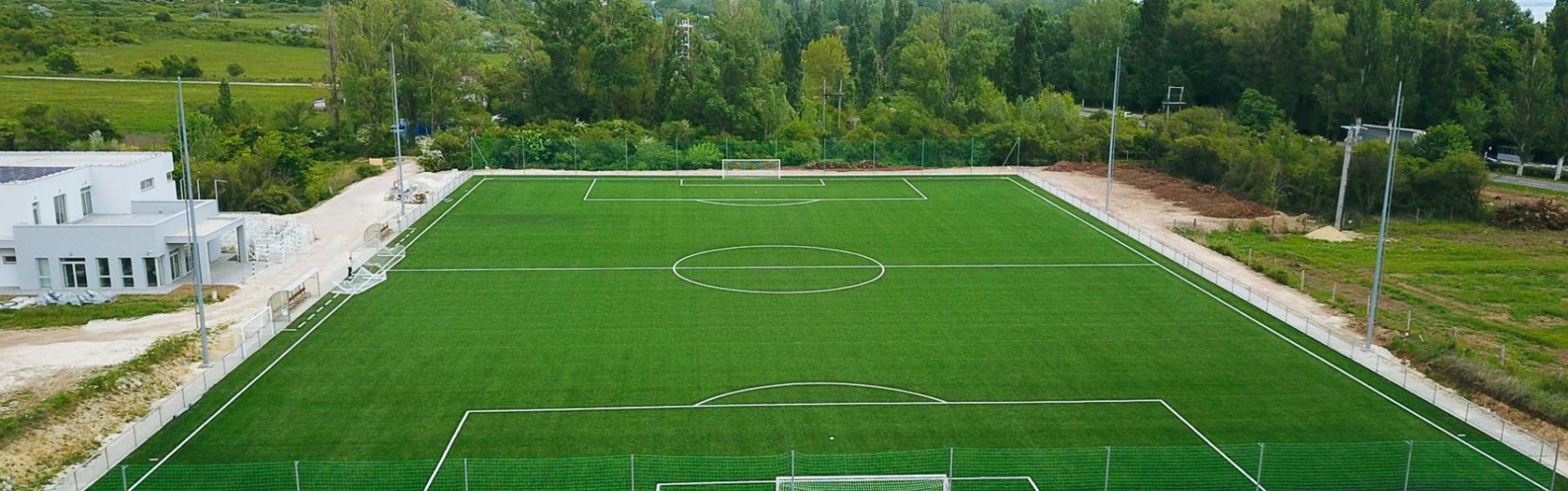 Panoramaaufnahme eines Fußballfeldes mit klaren Linien, in einer ländlichen Gegend..