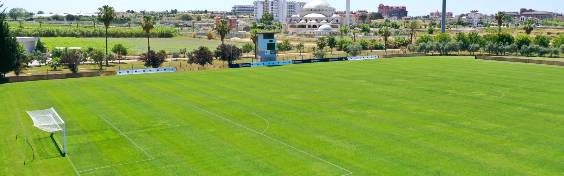  Fu&szlig;ballfeld in Side mit gr&uuml;ner Umgebung, perfektem Spielfeld und einer beeindruckenden Moschee im Hintergrund.