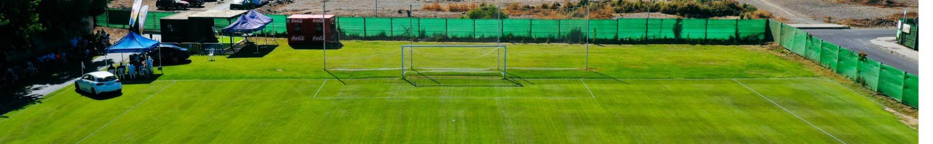 Ein idyllisches Spielfeld mit Naturrasen, eingerahmt von Palmen und weiten Landschaften.