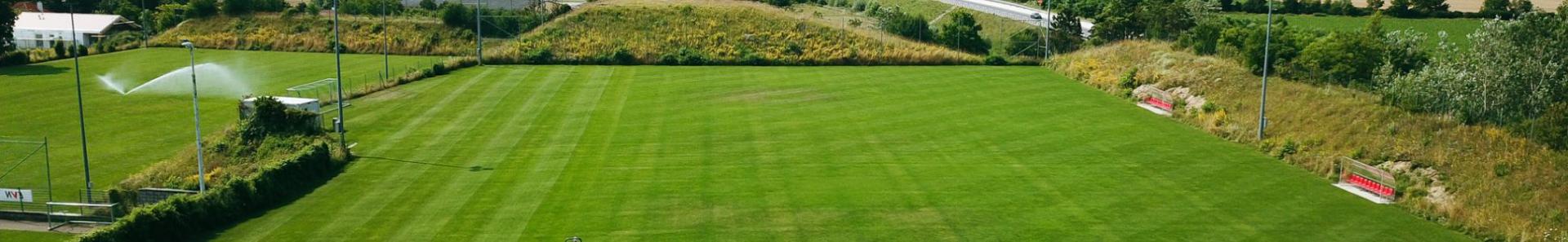 Fu&szlig;balltrainingsplatz in Nieder&ouml;sterreich, eingebettet in eine l&auml;ndliche Landschaft mit Blick auf Felder, Windr&auml;der und eine Landstra&szlig;e.