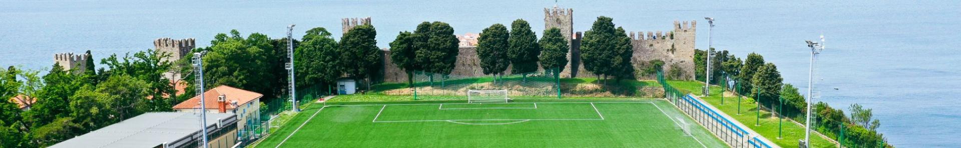Fußballplatz direkt am Meer mit historischem Burgmauer-Hintergrund, ideal für ein Trainingslager in einzigartiger Kulisse.