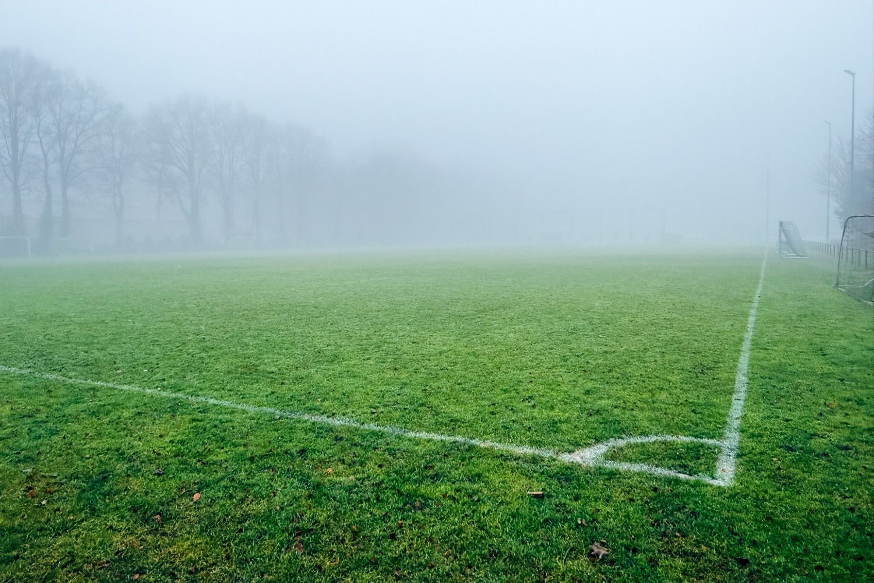Ein nebliger Tag im Sporthotel Bruurs in Baarle-Nassau: Die weißen Markierungen des Fußballplatzes, die Bäume und die Torpfosten sind während des Trainingslagers teilweise vom dichten Nebel verdeckt.