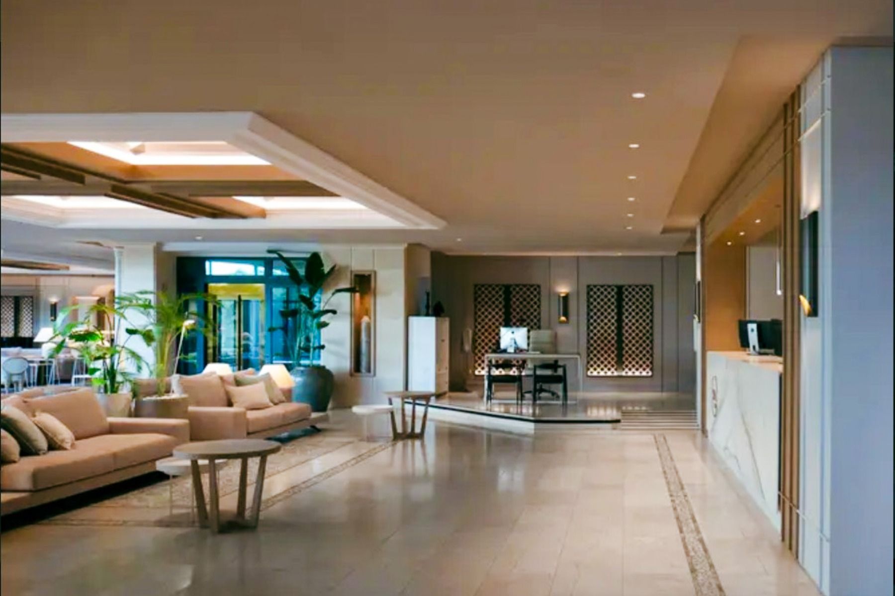 Die geräumige, moderne Lobby des Hotels SH Villa Gadea* ist mit beigen Sofas, runden Tischen, Topfpflanzen und einer Rezeption aus Marmor ausgestattet. Große Fenster und dekorative Paneele sorgen für eine einladende Atmosphäre in der Nähe der Sportanlagen