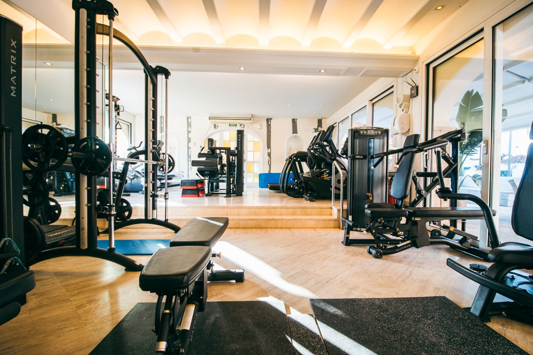 Moderner Fitnessraum im Van der Valk Hotel BARCAROLA an der Costa Brava mit diversen Trainingsgeräten, Hantelbänken und Cardiogeräten. Der helle, saubere Raum mit großen Spiegeln ist ideal für ein Fußball-Trainingslager.