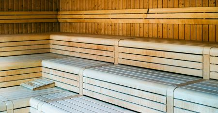 Das Sporthotel Bruurs ist ein modernes zweist&ouml;ckiges Geb&auml;ude mit gelben D&auml;chern und Wellness-Schildern, umgeben von gr&uuml;nen Hecken und B&auml;umen in Baarle-Nassau unter einem teilweise bew&ouml;lkten Himmel - ideal f&uuml;r ein Trainingslager.