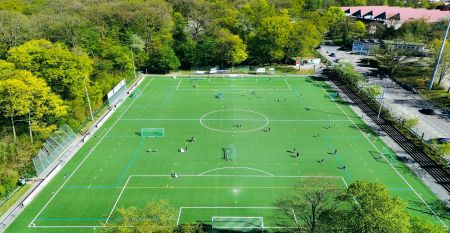 Luftaufnahme des von B&auml;umen umgebenen Sportparks Fun4You mit gro&szlig;em Solargeb&auml;ude, Spielplatz, Teambuilding-Seilgarten, Sportpl&auml;tzen, Parkplatz und bewaldeter Umgebung.