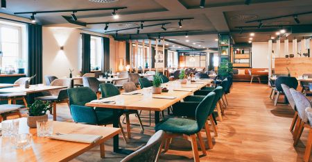 Der Hanauer Hof, ein gro&szlig;es traditionelles Hotel mit Ziegeldach und gr&uuml;nen Fensterl&auml;den, steht an einer Stra&szlig;enecke in Appenweier. Autos sind drau&szlig;en geparkt, Sonnenkollektoren s&auml;umen das Dach, und ein Kunstrasenplatz ist unter dem klaren blauen Himmel ni