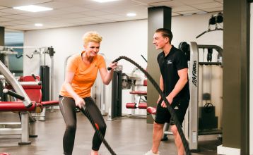 Das Sporthotel Bruurs ist ein modernes zweistöckiges Gebäude mit gelben Dächern und Wellness-Schildern, umgeben von grünen Hecken und Bäumen in Baarle-Nassau unter einem teilweise bewölkten Himmel - ideal für ein Trainingslager.