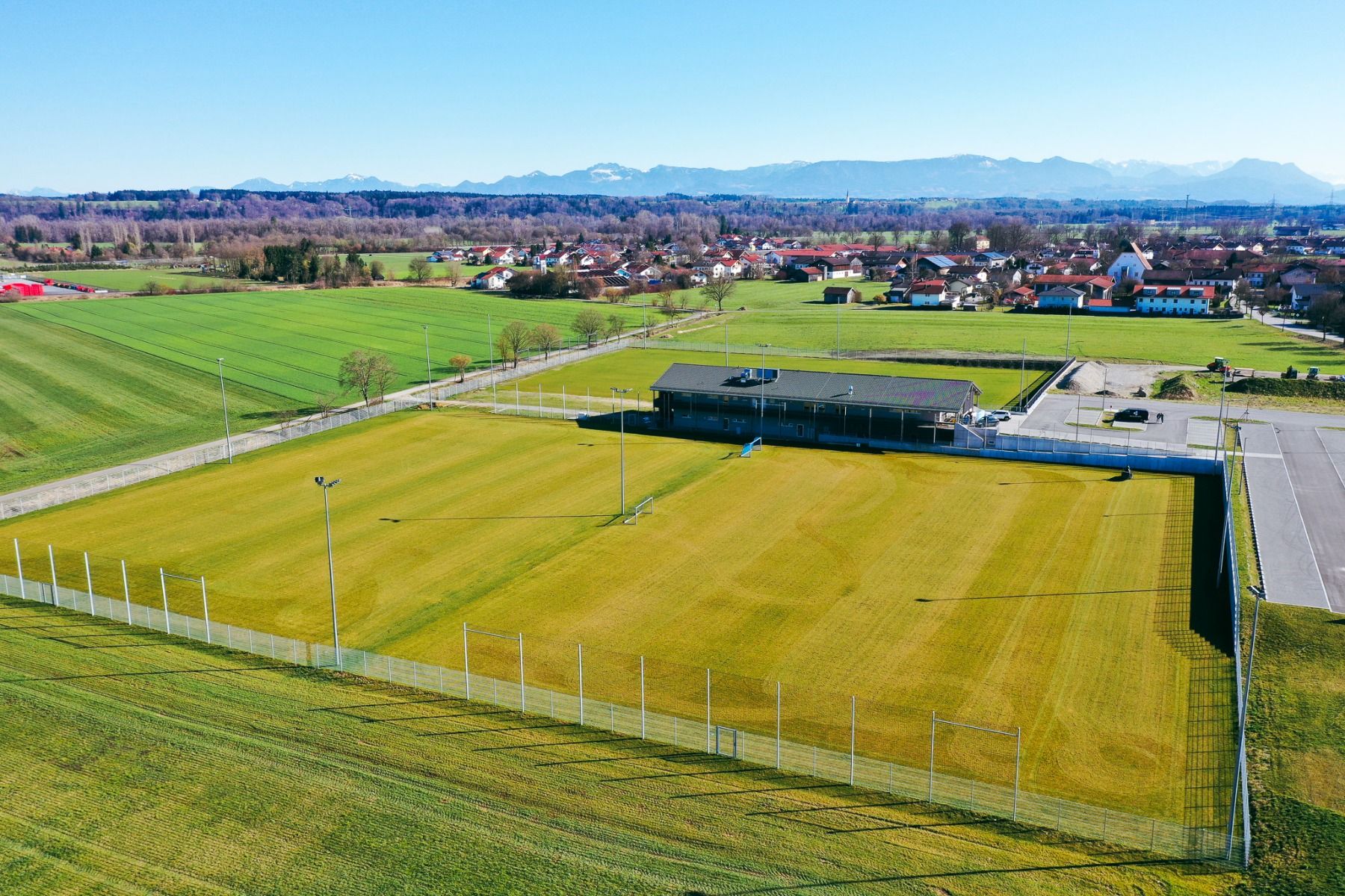 Aerial view of the well-maintained Egger Stüberl soccer pitch next to a building and parking lot in a picturesque mountain village - an ideal soccer pitch for your next training camp.