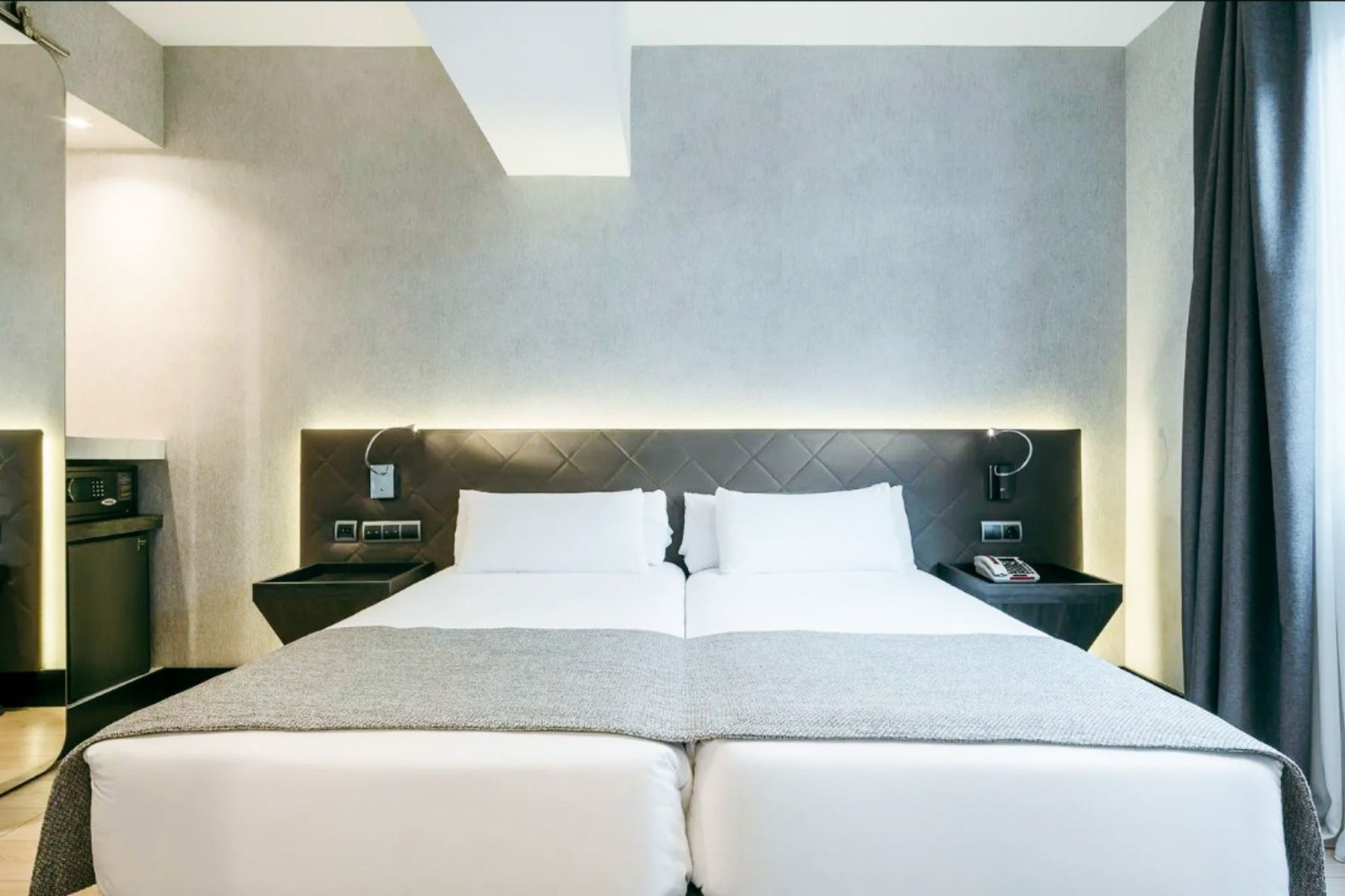 Hotel ILUNION Bel Art Barcelona tilbyr et moderne rom med to enkeltsenger sammen, hvitt sengetøy, grå pledd, polstret hodegjerde, nattbord, veggfestede leselamper og et vindu med gardiner - like ved de beste treningsfasilitetene i Barcelona.