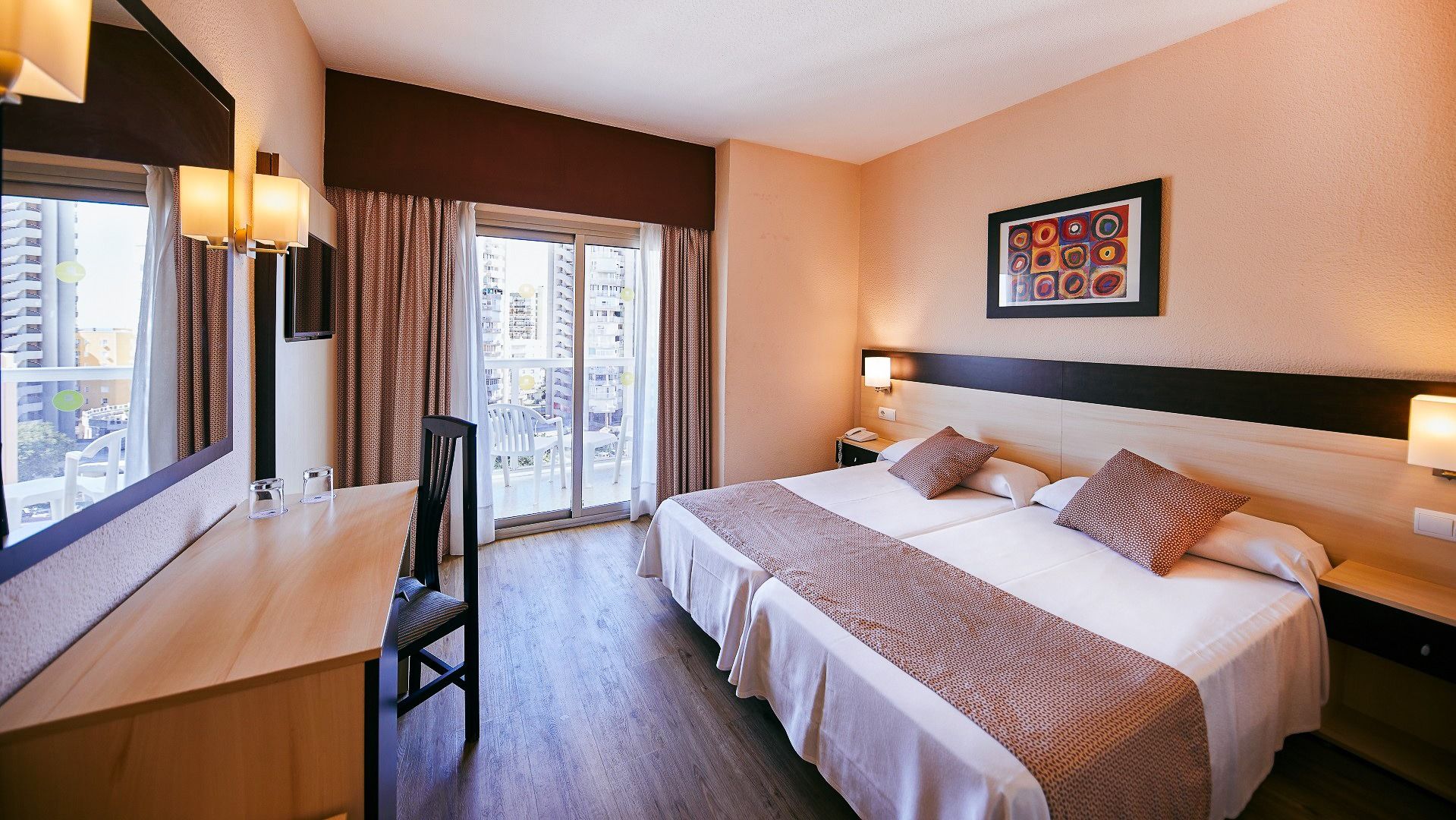 Hotelzimmer mit einem Doppelbett, Schreibtisch, Balkonzugang und Stadtblick.