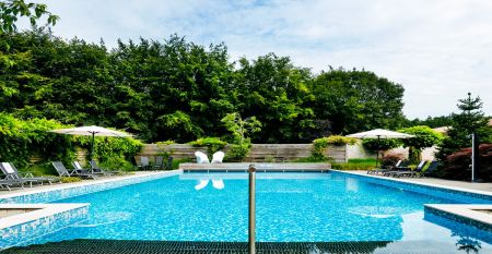 Das Sporthotel Bruurs ist ein modernes zweist&ouml;ckiges Geb&auml;ude mit gelben D&auml;chern und Wellness-Schildern, umgeben von gr&uuml;nen Hecken und B&auml;umen in Baarle-Nassau unter einem teilweise bew&ouml;lkten Himmel - ideal f&uuml;r ein Trainingslager.