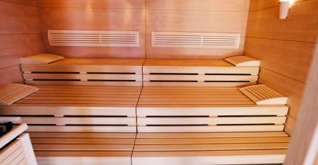 A bright yellow building in Neuhofen an der Ybbs with a jetty, ladder and black inflatable boat is situated on a quiet pond in the countryside - people enjoy this scene at the family-run Hotel Perbersdorfer Heuriger.