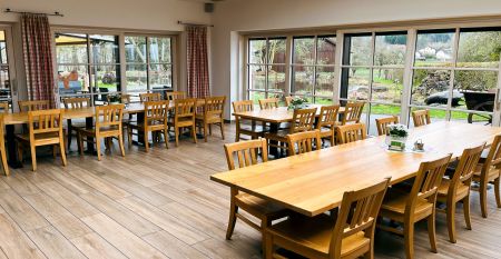 A bright yellow building in Neuhofen an der Ybbs with a jetty, ladder and black inflatable boat is situated on a quiet pond in the countryside - people enjoy this scene at the family-run Hotel Perbersdorfer Heuriger.