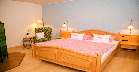 A bright yellow building in Neuhofen an der Ybbs with a jetty, ladder and black inflatable boat is situated on a quiet pond in the countryside - people enjoy this scene at the family-run Hotel Perbersdorfer Heuriger.