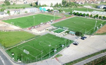 Appartements Residence Eden*** is a sunny Italian residential complex near Parc Hotel at Lake Garda, with yellow and terracotta buildings, red-tiled roofs, balconies, and a landscaped courtyard with lawns, shrubs, paths, and globe lamp posts.