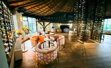 Hotel De Beyaerd’s bright, modern restaurant features large glass walls, light wood floors, and stylish gray and yellow chairs—an ideal setting for teambuilding activities surrounded by lush greenery.