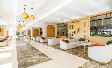 The Side Moon Palace is a modern hotel with several floors and balconies from which guests can enjoy a view of a spacious outdoor pool lined with rows of white lounge chairs and closed umbrellas.