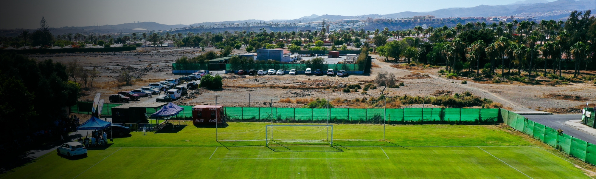 Ein idyllisches Spielfeld mit Naturrasen, eingerahmt von Palmen und weiten Landschaften.