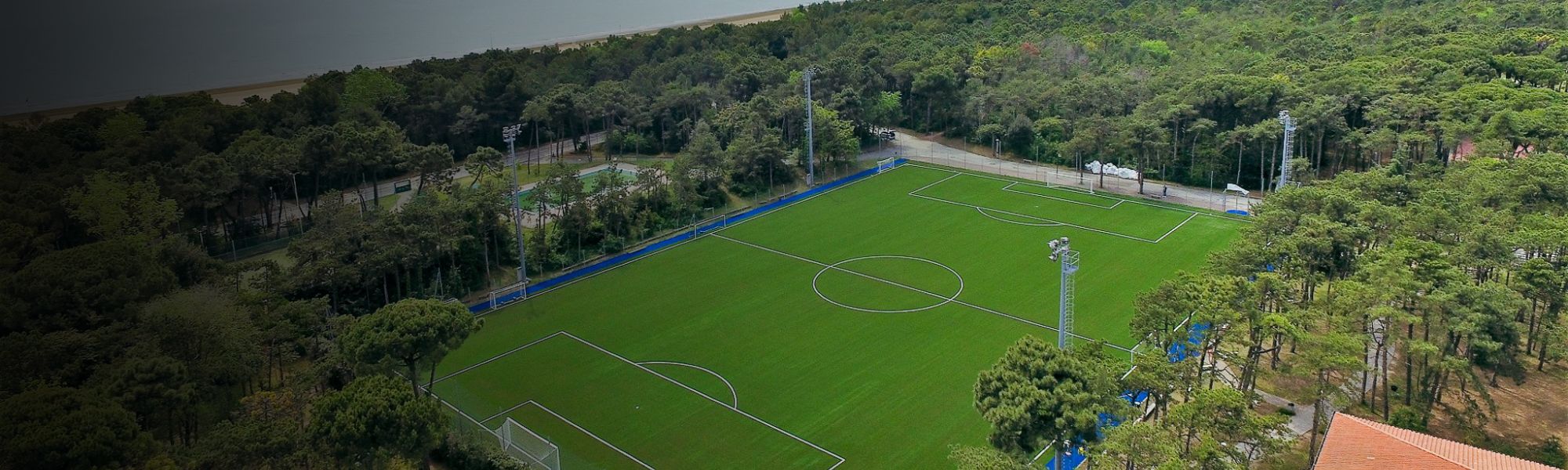 uftaufnahme eines Fußballplatzes an der Oberen Adria, umgeben von Pinienwald.