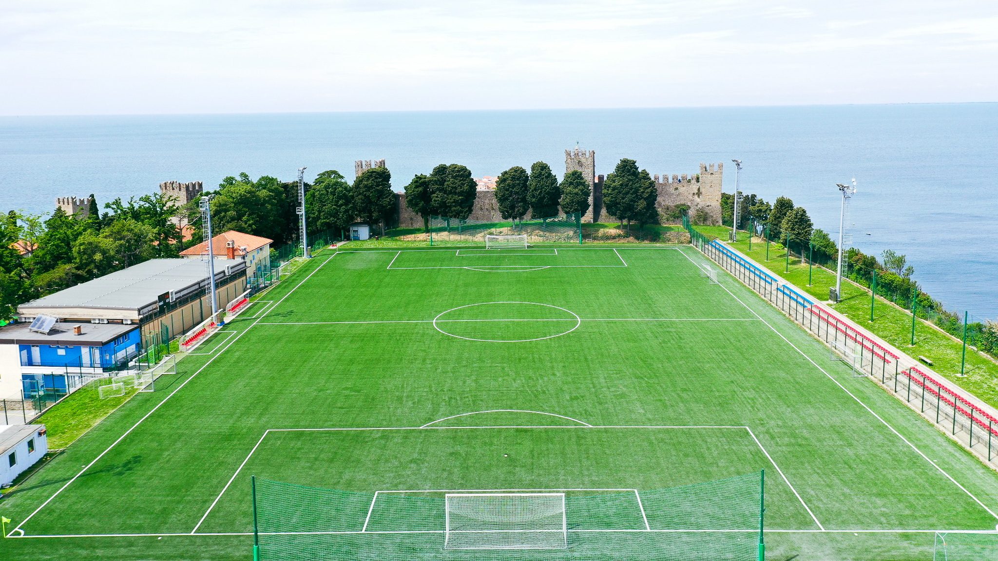 Fußballplatz direkt am Meer mit historischem Burgmauer-Hintergrund, ideal für ein Trainingslager in einzigartiger Kulisse.