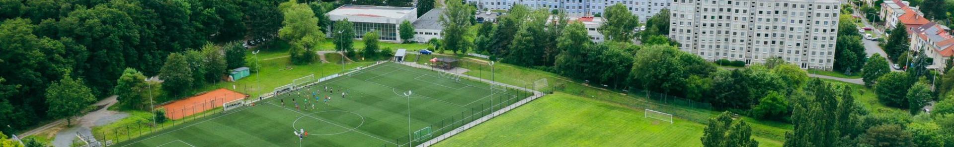 Voetbalveld midden in een groen landschap met uitzicht op een stad met veel hoge gebouwen.