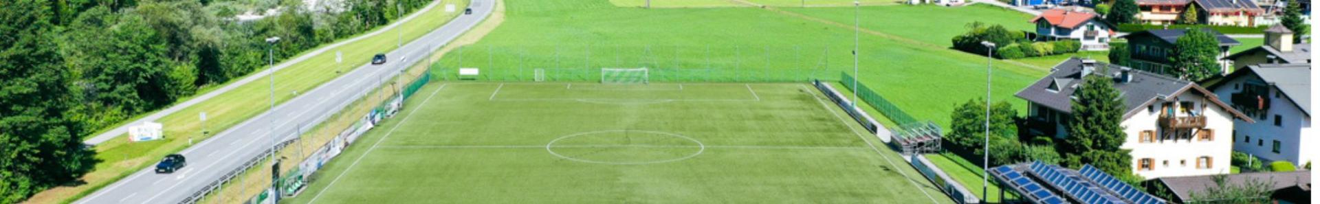 Voetbalveld in de Oostenrijkse Alpen, omringd door bergen en weiden.