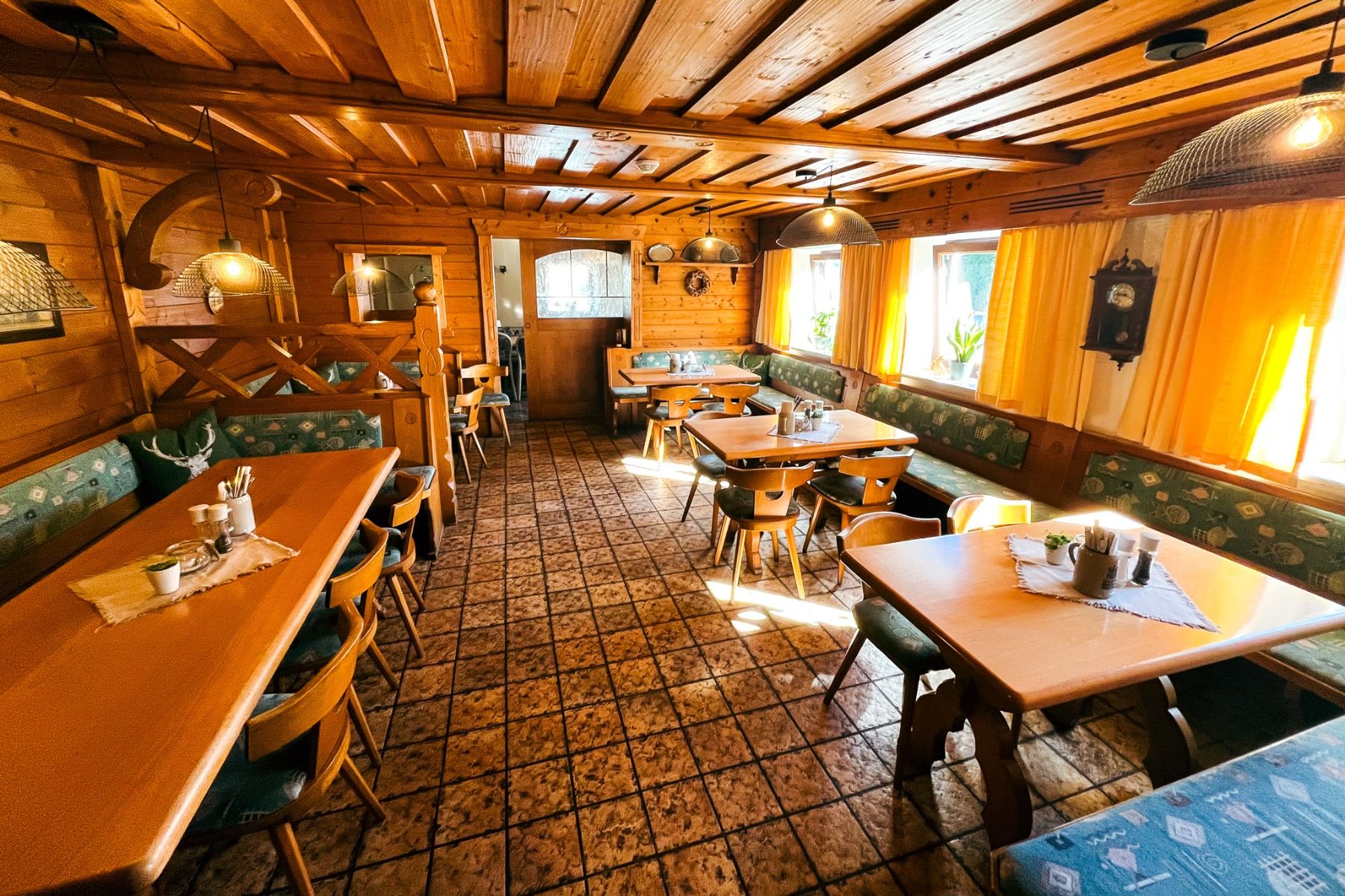 De Egger Stüberl is een gezellig, rustiek restaurant met een houten interieur, tegelvloeren met patroon, gestoffeerde banken en warm zonlicht door gele gordijnen - ideaal om te ontspannen na een bezoek aan de nabijgelegen voetbalvelden.