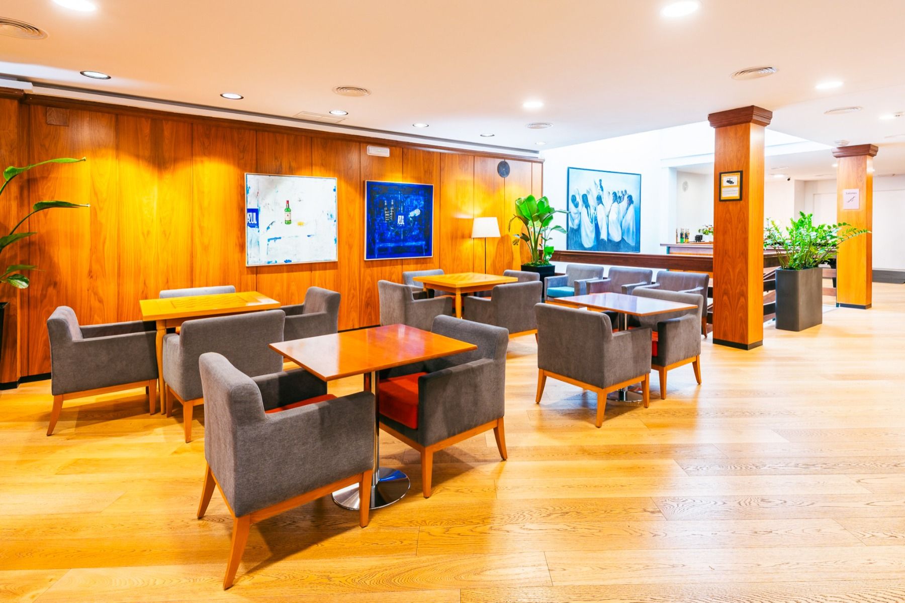 De moderne lounge in Hotel Borgia *** valt op door zijn elegante houten vloeren en wanden, talrijke tafels met grijze gestoffeerde fauteuils, sfeervolle verlichting, weelderige planten en kleurrijke abstracte kunstwerken – en vormt zo een stijlvol toevluc