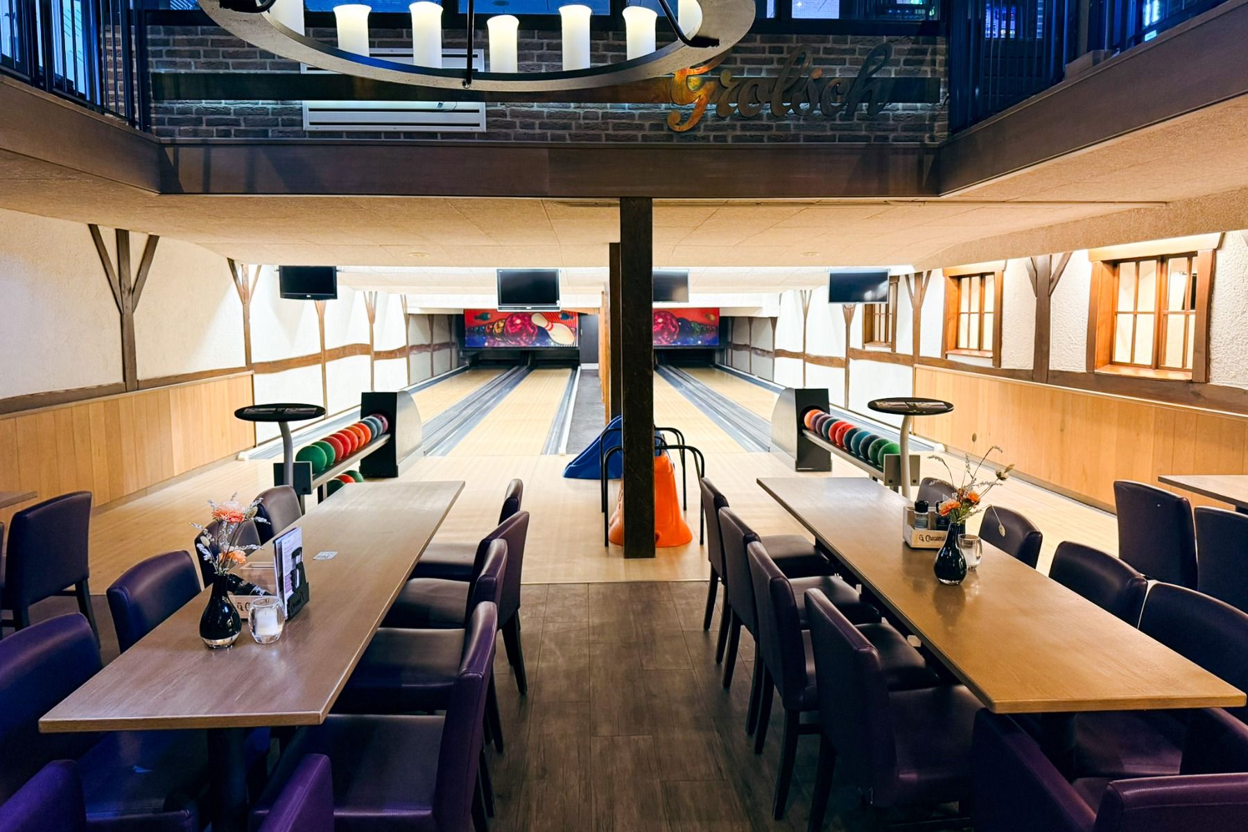 Marveld Recreatie, in een vakantiepark bij Groenlo, biedt een bowlingbaan met twee banen met kleurrijke ballen, paarse stoelen, tv-schermen en overheadverlichting - een leuke plek voor gasten die in nabijgelegen bungalows verblijven.