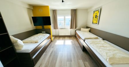 Luchtfoto van Champions-Park in Freudenstadt, met een rode atletiekbaan rond een grasveld, twee felgroene kunstvoetbalvelden die perfect zijn voor een voetbaltrainingskamp, gebouwen, parkeerplaatsen en groenstroken.