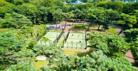 Duinrell is een modern huis van twee verdiepingen met een metalen dak, grote ramen en een houten buitenkant in de buurt van sportinfrastructuur. Geniet van een overdekte patio met buiteneten en meubilair op een verzorgd gazon omringd door bomen onder de b
