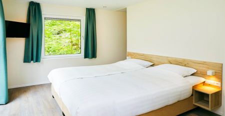 Duinrell is een modern huis van twee verdiepingen met een metalen dak, grote ramen en een houten buitenkant in de buurt van sportinfrastructuur. Geniet van een overdekte patio met buiteneten en meubilair op een verzorgd gazon omringd door bomen onder de b