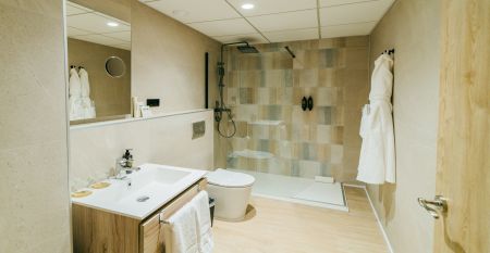 Buitenaanzicht van Hotel Gaudea met grote glazen ramen die een helder verlichte, stijlvolle lobby en bar tonen - op slechts een paar minuten van het strand van Santa Pola.