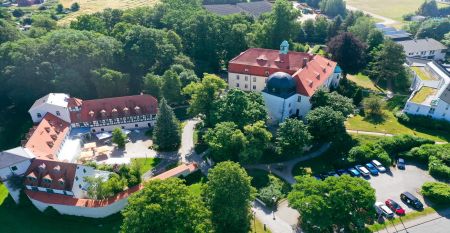 Hotel Schloss Schweinsburg is een prachtig historisch landhuis met een rood pannendak en grote ramen, dat uitzicht biedt op goed onderhouden tuinen met een rechthoekige vijver, heggen, bankjes, hoge bomen en nabijgelegen sportvelden waar u onder een strak
