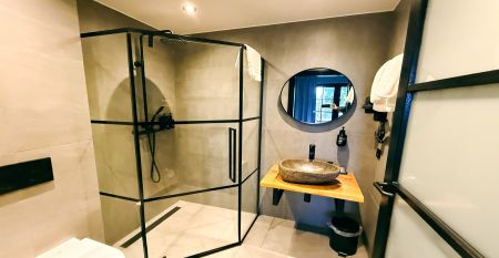 Hotel De Beyaerd biedt een ruim, modern restaurant met grote glazen ramen, lichthouten tafels, grijze en mosterdkleurige stoelen, hangende potplanten en uitzicht op bomen - ideaal voor teambuildingsactiviteiten.