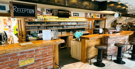 Een knalgeel gebouw in Neuhofen an der Ybbs met een steiger, ladder en zwarte opblaasboot ligt aan een rustige vijver op het platteland - mensen genieten van dit tafereel in het door een familie gerunde Hotel Perbersdorfer Heuriger.