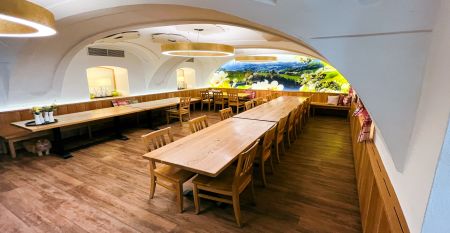 Een knalgeel gebouw in Neuhofen an der Ybbs met een steiger, ladder en zwarte opblaasboot ligt aan een rustige vijver op het platteland - mensen genieten van dit tafereel in het door een familie gerunde Hotel Perbersdorfer Heuriger.