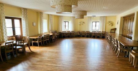 Een knalgeel gebouw in Neuhofen an der Ybbs met een steiger, ladder en zwarte opblaasboot ligt aan een rustige vijver op het platteland - mensen genieten van dit tafereel in het door een familie gerunde Hotel Perbersdorfer Heuriger.