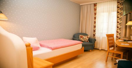 Een knalgeel gebouw in Neuhofen an der Ybbs met een steiger, ladder en zwarte opblaasboot ligt aan een rustige vijver op het platteland - mensen genieten van dit tafereel in het door een familie gerunde Hotel Perbersdorfer Heuriger.