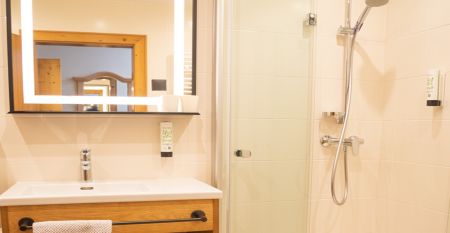 Een knalgeel gebouw in Neuhofen an der Ybbs met een steiger, ladder en zwarte opblaasboot ligt aan een rustige vijver op het platteland - mensen genieten van dit tafereel in het door een familie gerunde Hotel Perbersdorfer Heuriger.