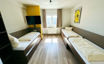 Luchtfoto van Champions-Park in Freudenstadt, met een rode atletiekbaan rond een grasveld, twee felgroene kunstvoetbalvelden die perfect zijn voor een voetbaltrainingskamp, gebouwen, parkeerplaatsen en groenstroken.